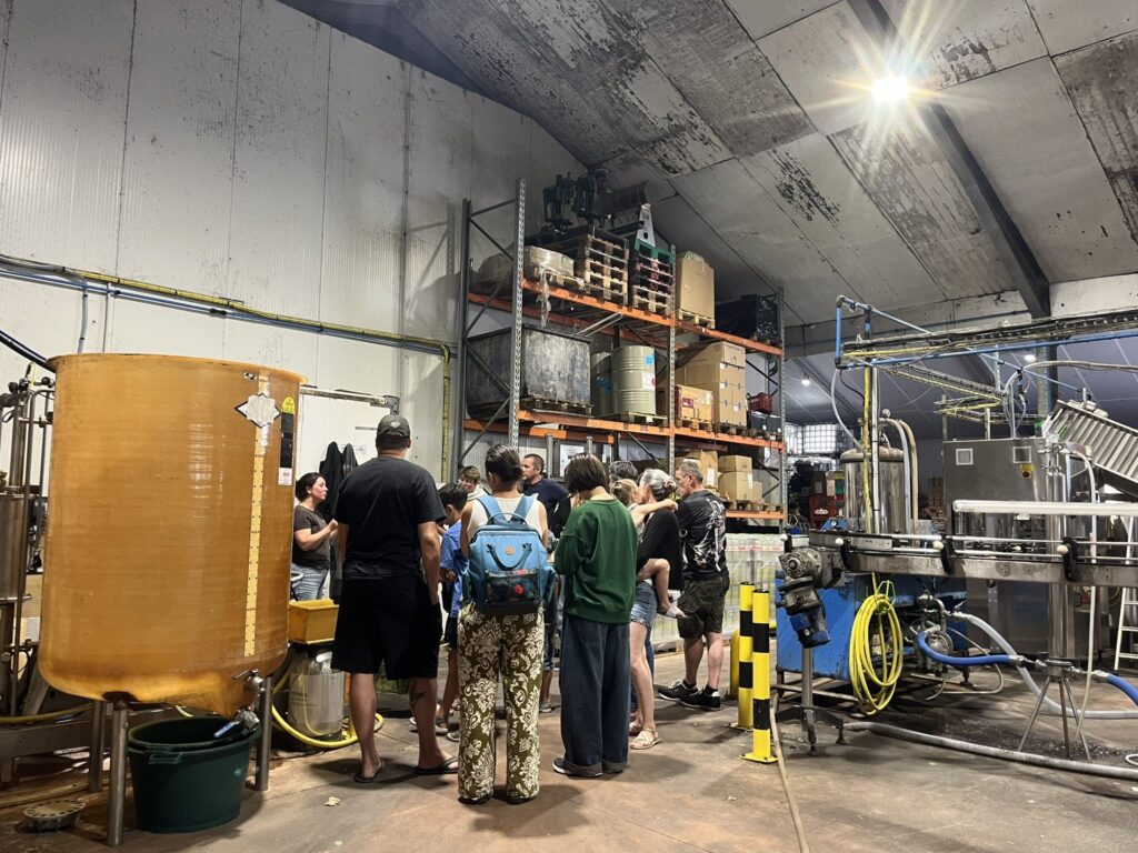 Groupe en visite dans l'atelier intérieur du P'tit Fausset près de la ligne et des cuves