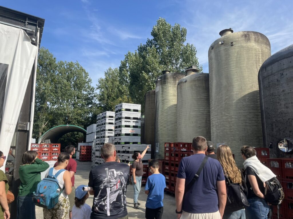 Guide montrant les grandes cuves extérieures aux visiteurs du P'tit Fausset